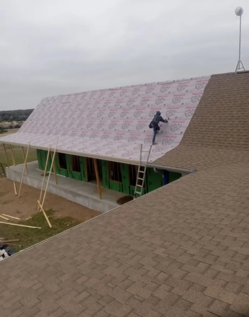 Worker preparing underlayment for a metal roof installation in Wilkins